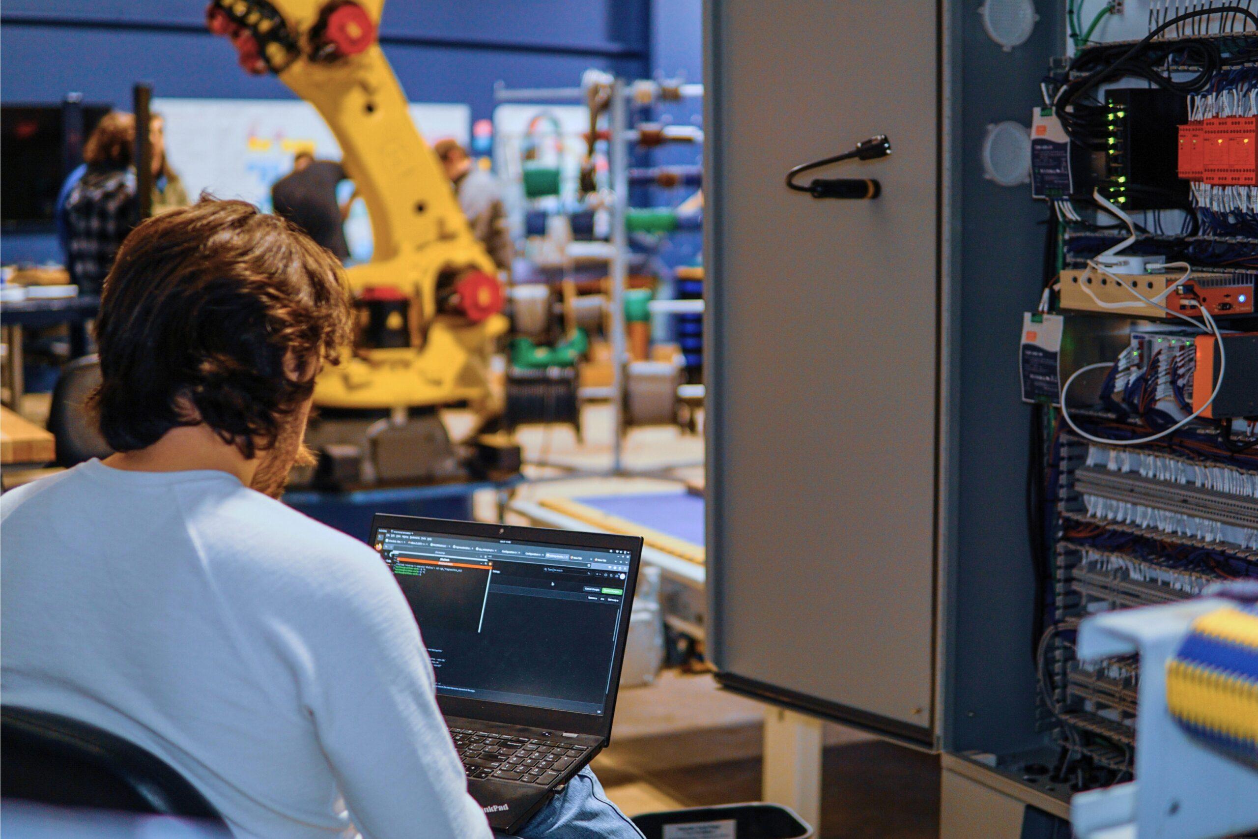 Rigorous employee working on code next to the power and control cabinet.