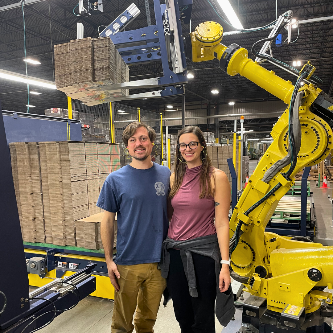 Rigorous co-founders standing proudly next to integrated Box Hopper robot.